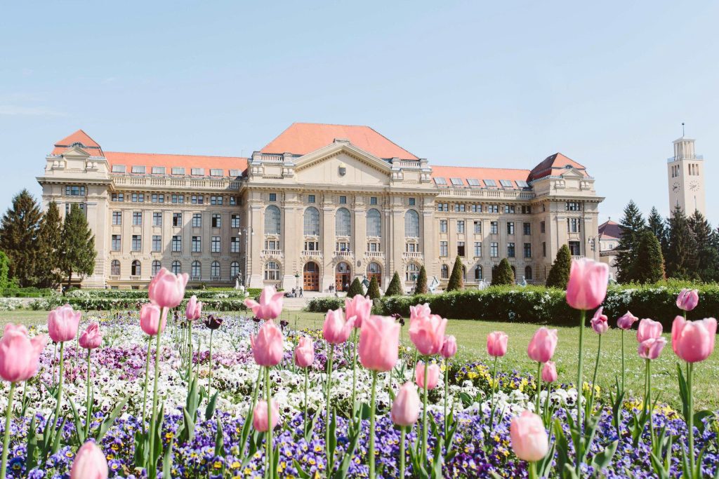Khuôn viên trường đại học tại Hungary với tòa nhà cổ kính và vườn hoa tulip